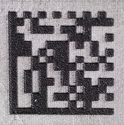 A data matrix code that was created with laser etching, forming a raised mark.