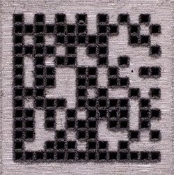 A data matrix code that was created with laser engraving, forming a deep mark.